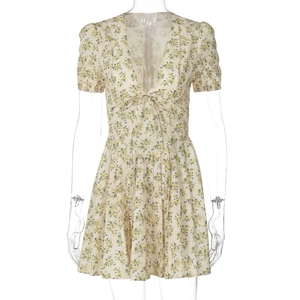 Détail du col en V et du nœud sur une robe d'été fleurie crème à manches courtes