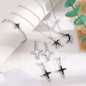Detail view of silver jewelry set featuring cross and moon bat pendants with black accents