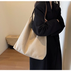 Detailed side view of suede tote bag with brown leather straps worn on a shoulder