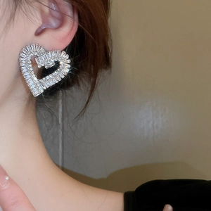 Gros plan d'une boucle d'oreille cœur de luxe sertie de zircons brillants portée par un modèle