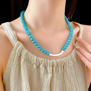 Collier ethnique en perles de turquoise avec tube en argent porté par un mannequin
