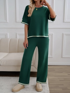 Close-up of dark green knitted set with elegant white stripe details on sleeves and hem