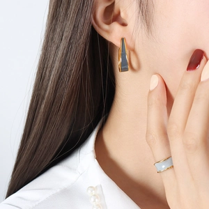 Fashionable gold earrings and ring set with grey enamel geometric design on female model