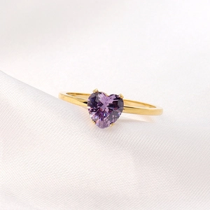 Elegant 18K gold heart-shaped ring with purple gemstone on white silk background