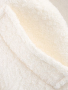 Detailed close-up showing the soft texture of white curly bouclé fabric on a winter coat