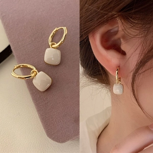 Boucles d'oreilles cœur carrées crème avec anneaux dorés sur velours violet et modèle