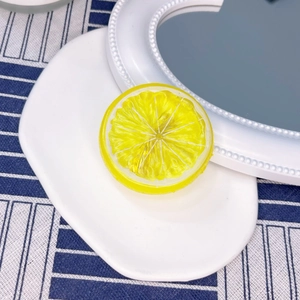 Detail showing realistic lemon slice hair clip with textured pulp and yellow rind finish
