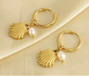 Vue détaillée des boucles d'oreilles coquillage doré avec perles sur satin beige