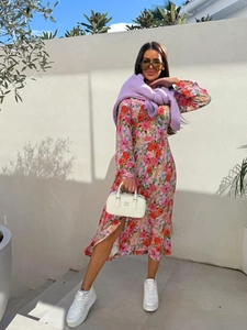 Outdoor street style of floral V-neck maxi dress with purple knit sweater over shoulders