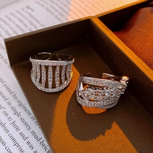 Macro detail of silver-tone hollow zircon open rings on a wooden jewelry display tray