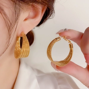 Detailed view of large gold mesh hoop earrings featuring a woven metal chain texture