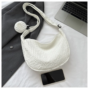 Detail of white pleated crescent bag with matching round coin purse on a bed