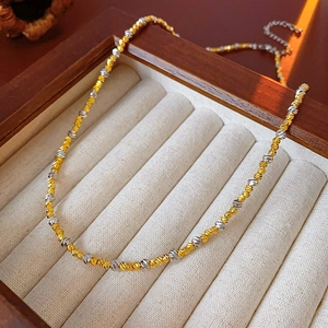 Macro detail of two-tone braided vintage necklace on a wooden jewelry display box