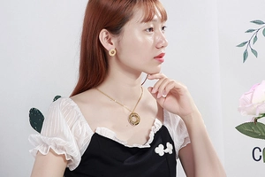 Close-up of gold stainless steel necklace and stud earrings with roman numerals and diamonds