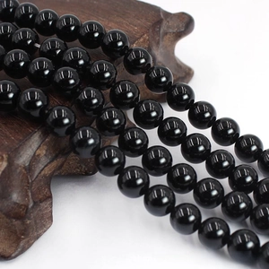 Macro shot of polished black agate round beads with mirror finish on wooden stand