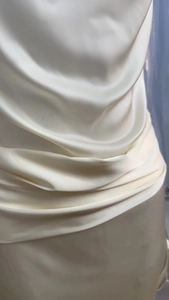 Dettaglio dell'elegante abito in raso avorio con trama in seta e pieghe drappeggiate