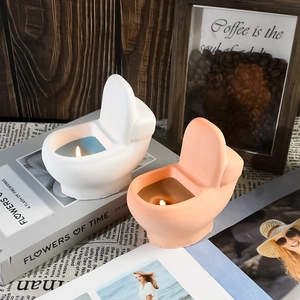 Detailed view of creative toilet-shaped scented candles in white and pink on books