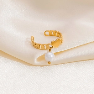 Detailed shot of golden hollow chain ring with heart motif and white pearl on silk