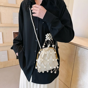 Elegant gold metal cage bag with white pearls and satin drawstring insert on a model