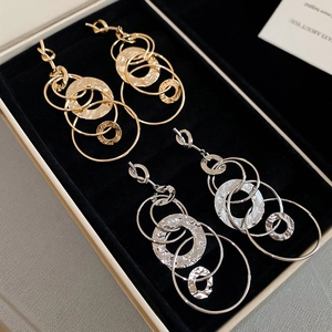 Detail of gold and silver multi-layer tiered metal drop earrings in a black jewelry box