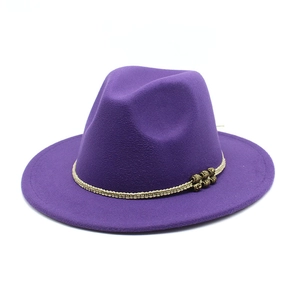 Detail of dark purple wool fedora hat with cream braided band and bronze metal accents