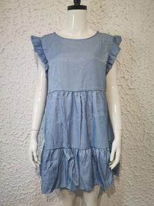 Detail showing the light blue sleeveless denim dress with ruffle sleeves and tiered hem