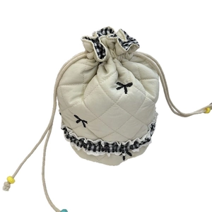 Quilted drawstring cosmetic bag in cream white with bow embroidery and ruffled edge