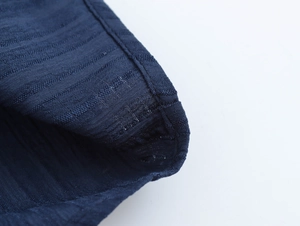Close-up of dark blue fabric texture showing delicate stitching and ruffle edge details