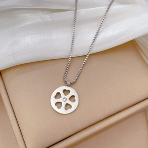 Macro detail of silver titanium steel circular pendant with heart cutouts and clear gem