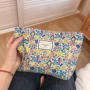 Close-up of floral cotton pouch featuring a Time to Party label and metal zipper