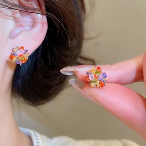 Close-up of colorful crystal flower stud earrings worn to show exquisite floral details