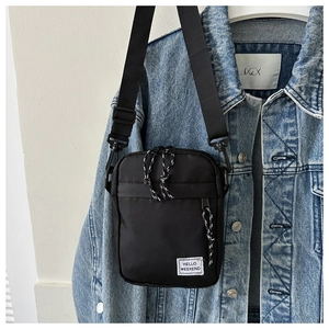 Detail of black nylon crossbody bag featuring Hello Weekend patch on denim jacket