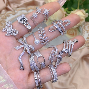 Macro shot of silver zircon rings with butterfly and bow motifs on model fingers