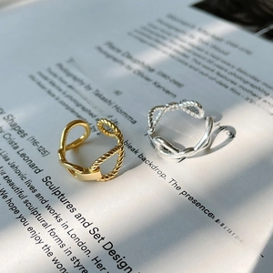 Detail of twisted woven design on gold and silver rings over elegant magazine pages