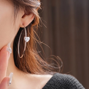 Boucles d'oreilles créoles C en argent avec zircon en cœur portées par un mannequin