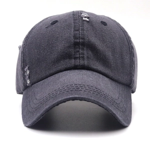 Dettaglio dell'effetto usurato su cappello in denim nero lavato con fori sfrangiati