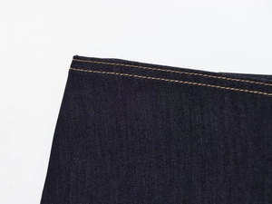 Gros plan des coutures jaunes contrastées sur denim bleu foncé à texture sergé
