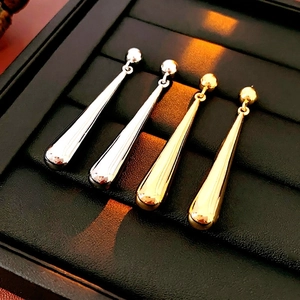 Minimalist metallic teardrop earrings in gold and silver finish displayed in jewelry box