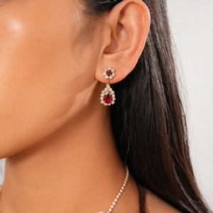 Close-up of vintage gold drop earrings with red gemstones worn by a fashion model