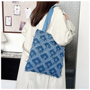 Macro detail of frayed denim tote bag with star patterns and checkered texture design