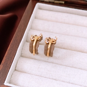 Detail of 18k gold plated vintage bow earrings with brown enamel and zircon inlay