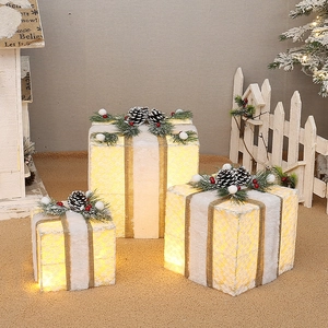 Detail of Christmas gift box trio with warm lights, pine cones and gold ribbons