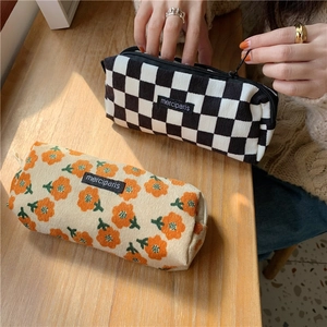 Detail of corduroy pencil cases in checkerboard and floral patterns on a wooden desk