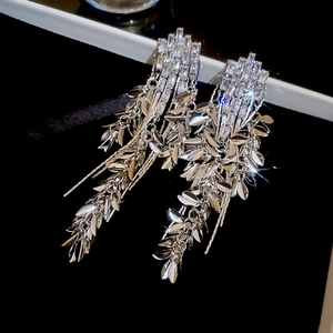 Macro detail of silver tassel earrings with wheat leaf design and sparkling zircons