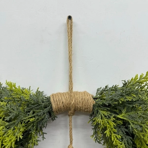 Detail of rustic jute rope hanging loop and realistic cedar branch holiday wreath texture