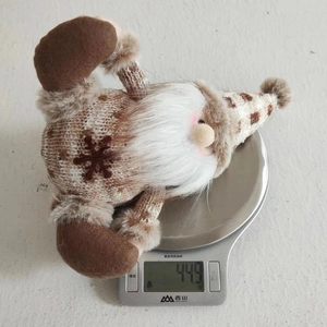 Detail shot of a knitted Christmas gnome plush weighing 44.9g on a digital scale