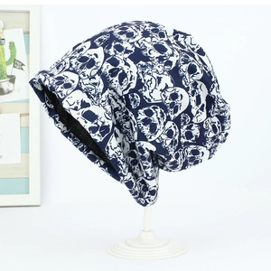 Detail of navy blue knit beanie featuring white skull patterns and soft cotton fabric