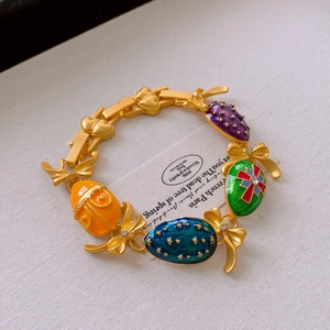 Detailed macro view of vintage bow and heart bracelet with colorful enamel egg charms