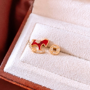 Détail de boucles d'oreilles plaquées or 18k avec cheval à bascule rouge et pièce