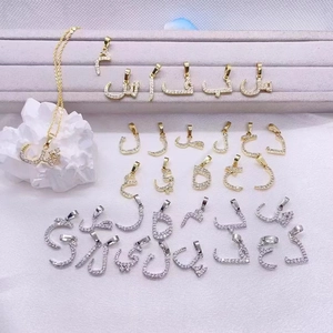 Macro shot of gold and silver Arabic letter pendants with clear crystals on fabric